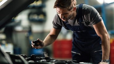 Young mechanic checking car coolant system in auto repair shop.